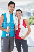 Fit couple with dumbbell and scale in bright exercise room