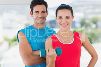 Fit couple with dumbbell in bright exercise room