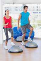 Couple performing on dome balance in bright gym