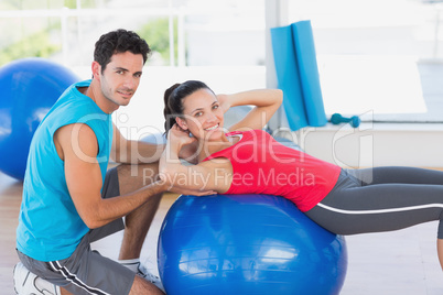 Male trainer helping woman with her exercises