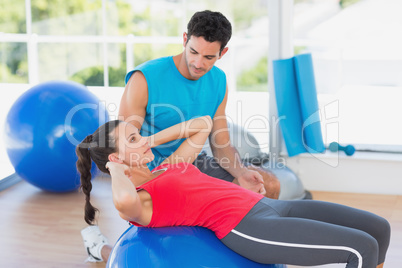 Male trainer helping woman with her exercises at gym