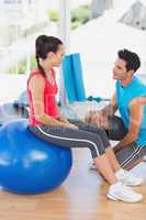 Instructor and woman with exercise ball at gym