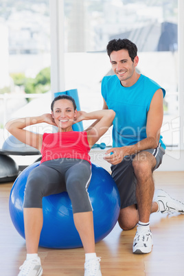 Male trainer helping woman with her exercises at gym