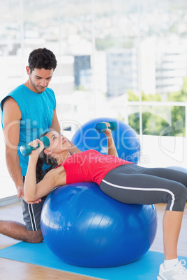 Trainer helping woman with her exercises at gym