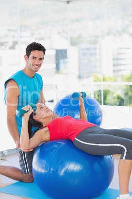 Trainer helping woman with her exercises at gym