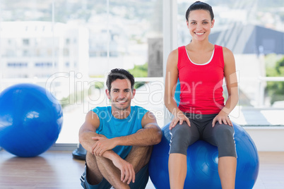 Instructor and smiling woman with exercise ball at gym