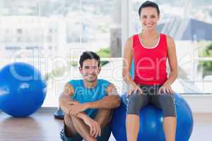 Instructor and smiling woman with exercise ball at gym