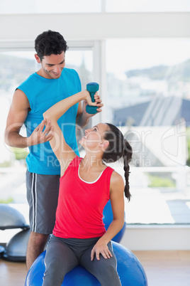 Male trainer helping woman with her exercises at gym