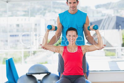 Male trainer helping woman with her exercises at gym