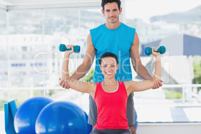 Male trainer helping woman with her exercises at gym