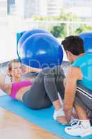 Trainer helping woman with her exercises at gym