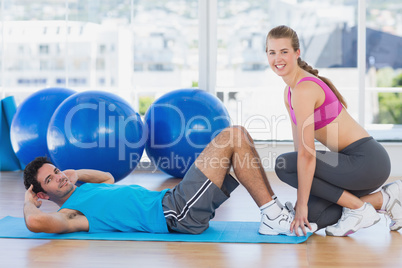 Female trainer helping man with his exercises at gym