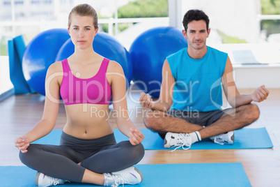 Young couple sitting in lotus posture at fitness studio