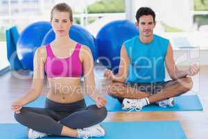 Young couple sitting in lotus posture at fitness studio