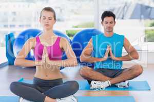 Couple with joined hands and eyes closed at fitness studio