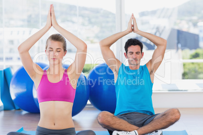 Couple with joined hands and eyes closed at fitness studio