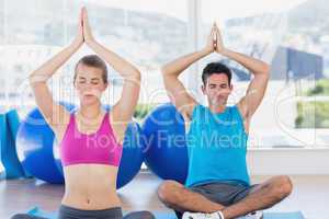 Couple with joined hands and eyes closed at fitness studio