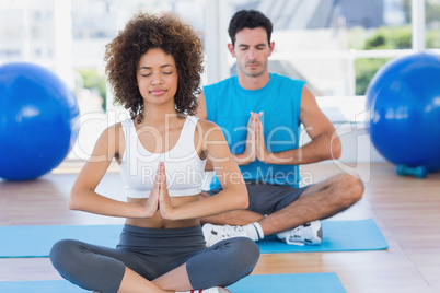Couple with joined hands and eyes closed at fitness studio