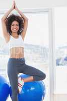 Fit smiling woman standing in tree pose at gym