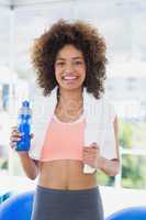 Fit young female holding water bottle at gym