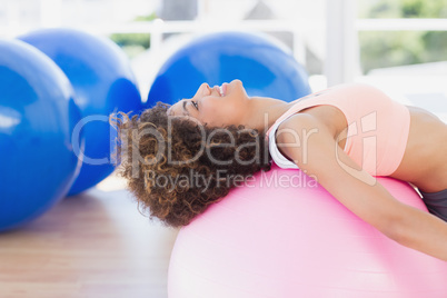 Side view of a fit young woman exercising on fitness ball