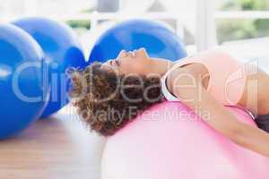 Side view of a fit young woman exercising on fitness ball