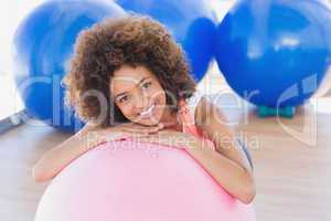 Smiling young woman with fitness ball at gym