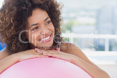 Fit smiling young woman with fitness ball at gym