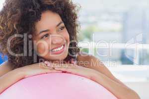 Fit smiling young woman with fitness ball at gym