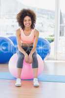 Portrait of a fit woman sitting on fitness ball at gym