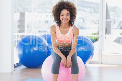 Fit young woman sitting on fitness ball at gym Fit young woman sitting on fitness ball at gym