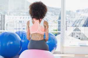 Rear view of a fit woman on fitness ball at gym