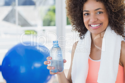 Fit young female holding water bottle at gym