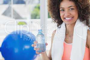 Fit young female holding water bottle at gym