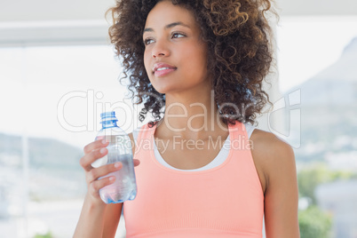 Fit female holding water bottle at gym