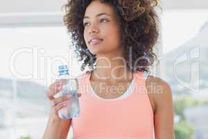 Fit female holding water bottle at gym