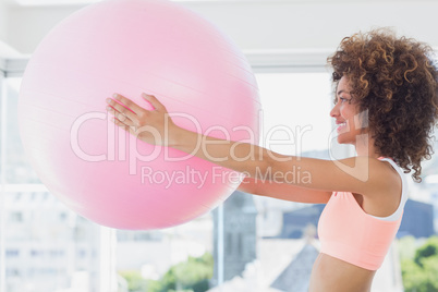 Sporty young woman holding ball in fitness studio