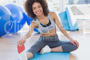 Fit woman stretching leg in fitness studio