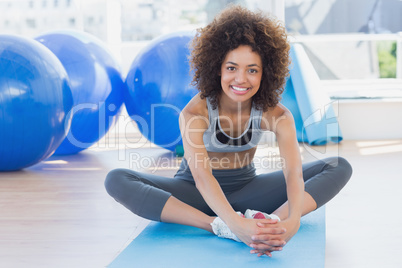Fit woman doing the butterfly stretch in exercise room