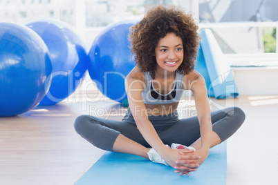 Fit woman doing the butterfly stretch in exercise room