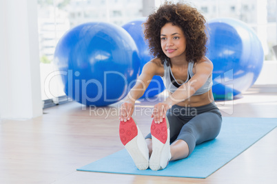 Sporty woman stretching hands to legs in fitness studio