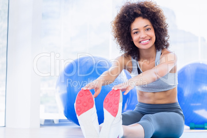 Sporty woman stretching hands to legs in fitness studio