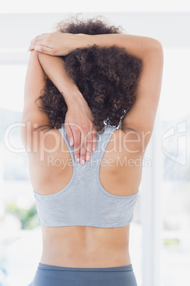 Sporty woman stretching hands behind back in fitness studio