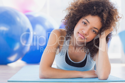 Fit woman lying on exercise mat in fitness studio