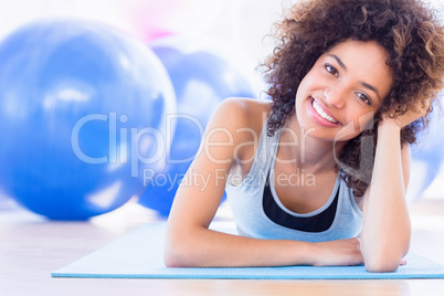 Fit woman lying on exercise mat in fitness studio