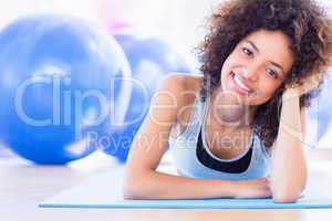 Fit woman lying on exercise mat in fitness studio