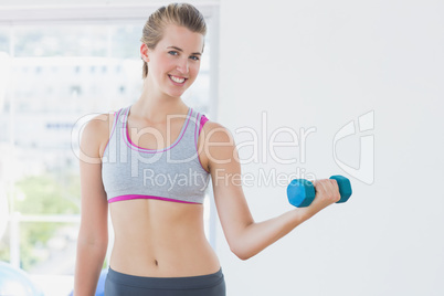 Young woman exercising with dumbbell in fitness studio