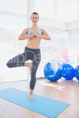 Fit smiling woman standing in tree pose