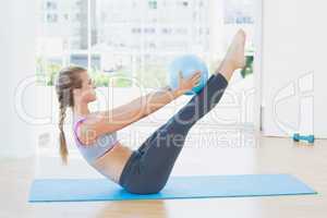 Sporty woman holding ball in fitness studio