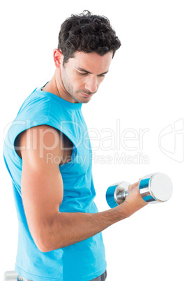Serious young man exercising with dumbbell